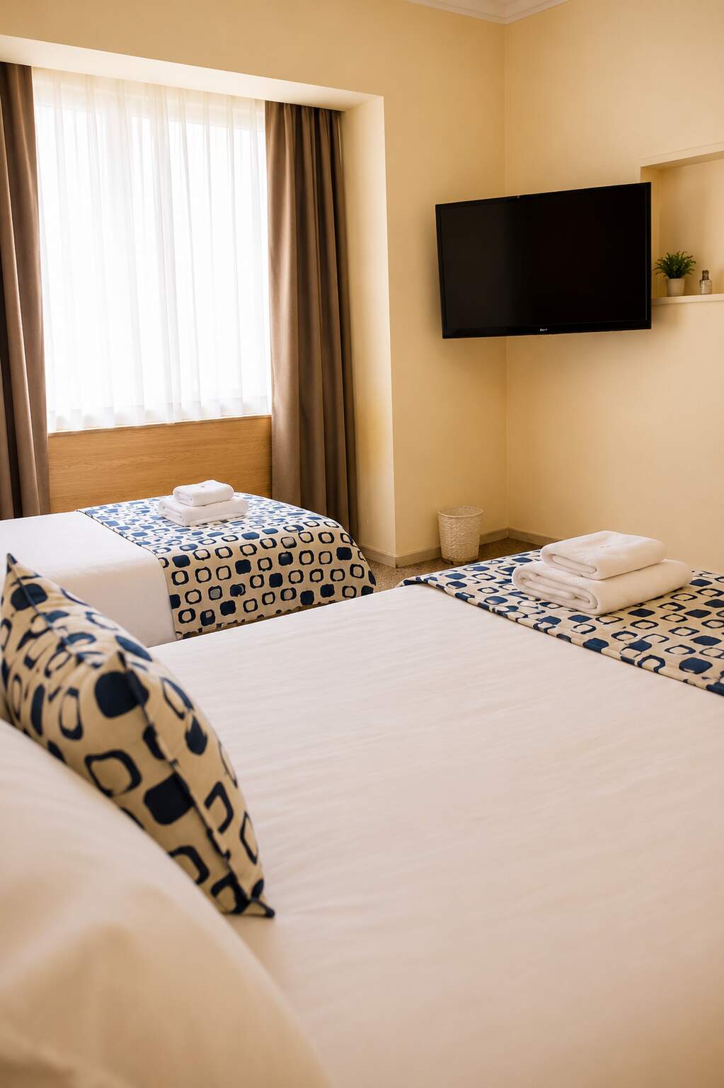 Comfortable guest room at Hotel Rondo with twin beds, fresh white linens and patterned blue runners