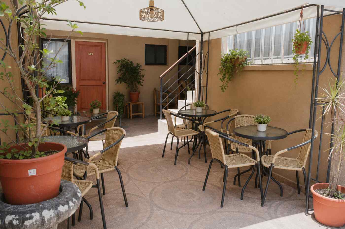 Covered courtyard terrace at Hotel Rondo Viña del Mar with café tables, wicker chairs and potted greenery