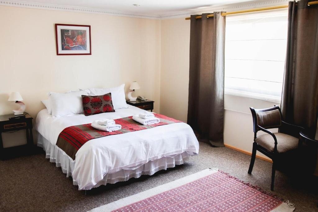 Double or deluxe double room at Hotel Rondo Viña del Mar with white bedding, red woven runner, bedside lamps and bright natural window light.